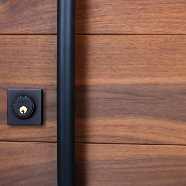 A wooden door with a black powder-coated door handle and matching lock