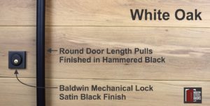 round black door hardware with matching black baldwin lock in front of white oak wood