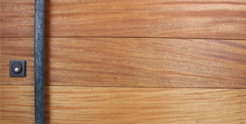 mahogany wood behind round modern door pulls and black baldwin square lock