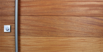 genuine mahogany wood door behind round brushed stainless steel door handles and matching stainless steel square door lock