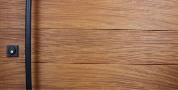 teak genuine wood door behind round black powder-coated door handle and square black door lock