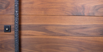 modern front door made of walnut wood with unique door hardware and baldwin square black lock