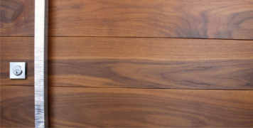 walnut wooden front door behind square polished modern door handles and square stainless steel door lock