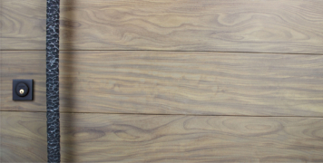 washed teak hardwood door behind hammered metal door pulls and black square door lock