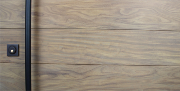 washed teak hardwood behind round black powder-coated door handles and matching square black lock