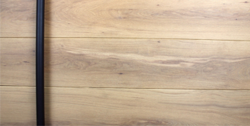 white oak hardwood door behind round black powder-coated door hardware