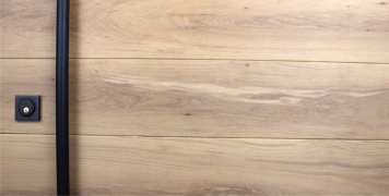white oak hardwood door behind round black powder-coated door hardware and square black door lock