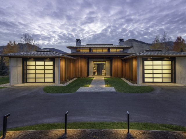 sleek, modern mountain home with a flat roof, large windows, and a minimalist design