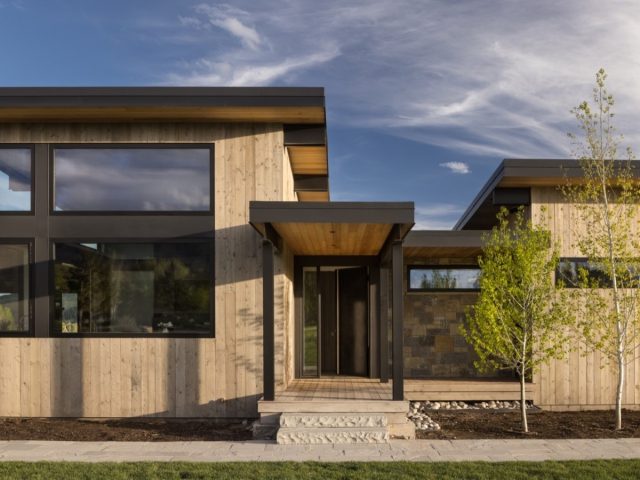 modern home with wood, stone finishes, large windows, and a sleek covered porch for a minimalist, inviting look