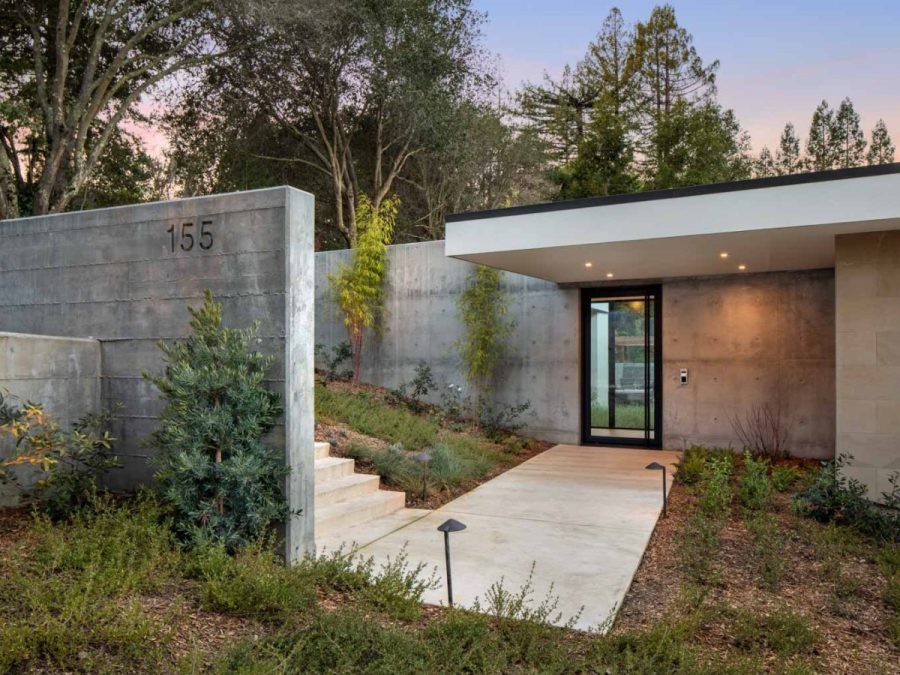 contemporary home with minimalist design, glass front door, concrete walls, and landscaped entry for a sleek, modern aesthetic