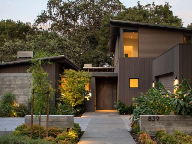 contemporary home with dark exterior, minimalist design, clean lines, lush landscaping, and modern landscape lighting