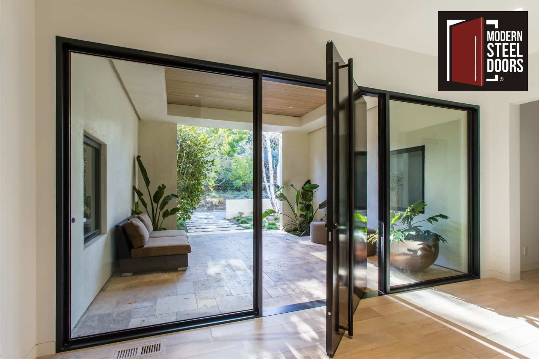 large modern steel pivot door with matching door hardware and large glass sidelights