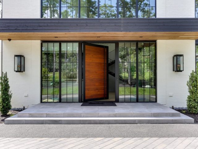 modern home entrance with large glass windows, oversized wood door, sleek design, and symmetrical lantern lighting