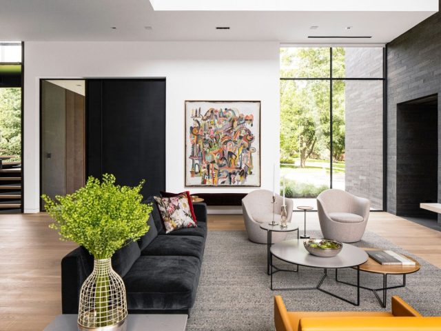 modern living room with black pivot door, floor-to-ceiling windows, vibrant artwork, and contemporary furniture
