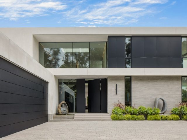modern home exterior with sleek black and white design, large glass windows, minimalist landscaping, and spacious driveway