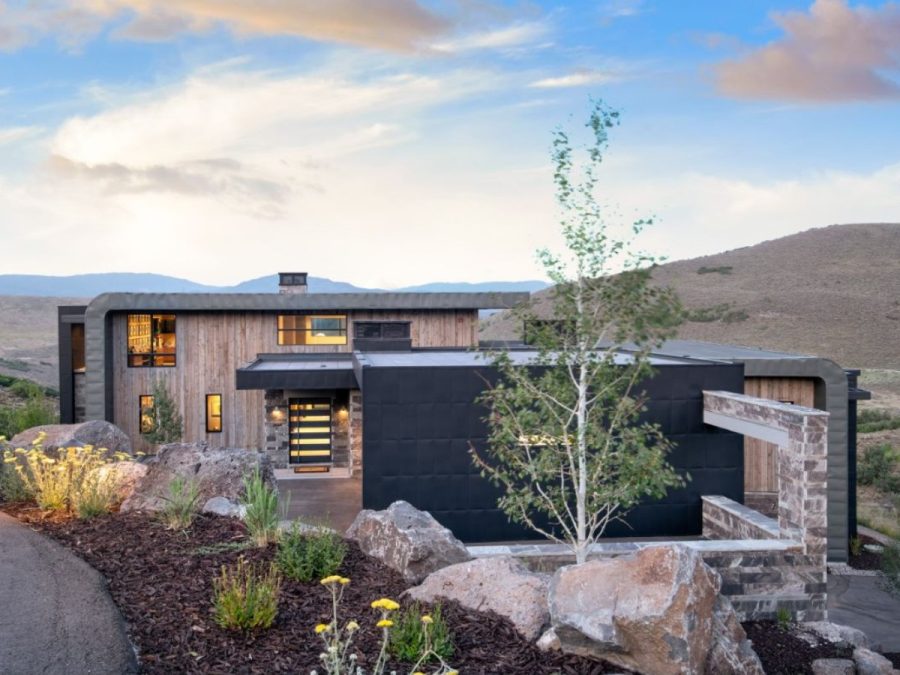 modern home in Park City with wood and stone accents, black metal facade, scenic mountain views, and xeriscaped landscaping